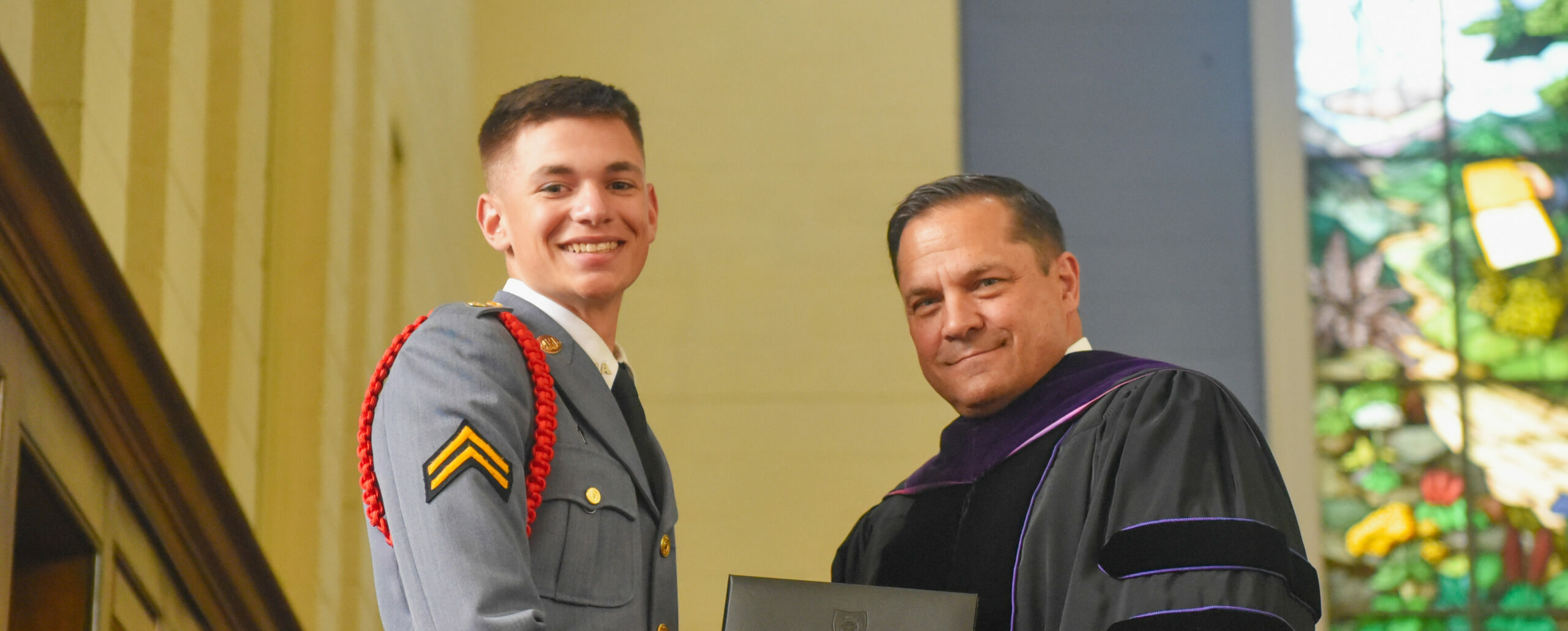 Cadet shaking hands with President while being handed diploma.