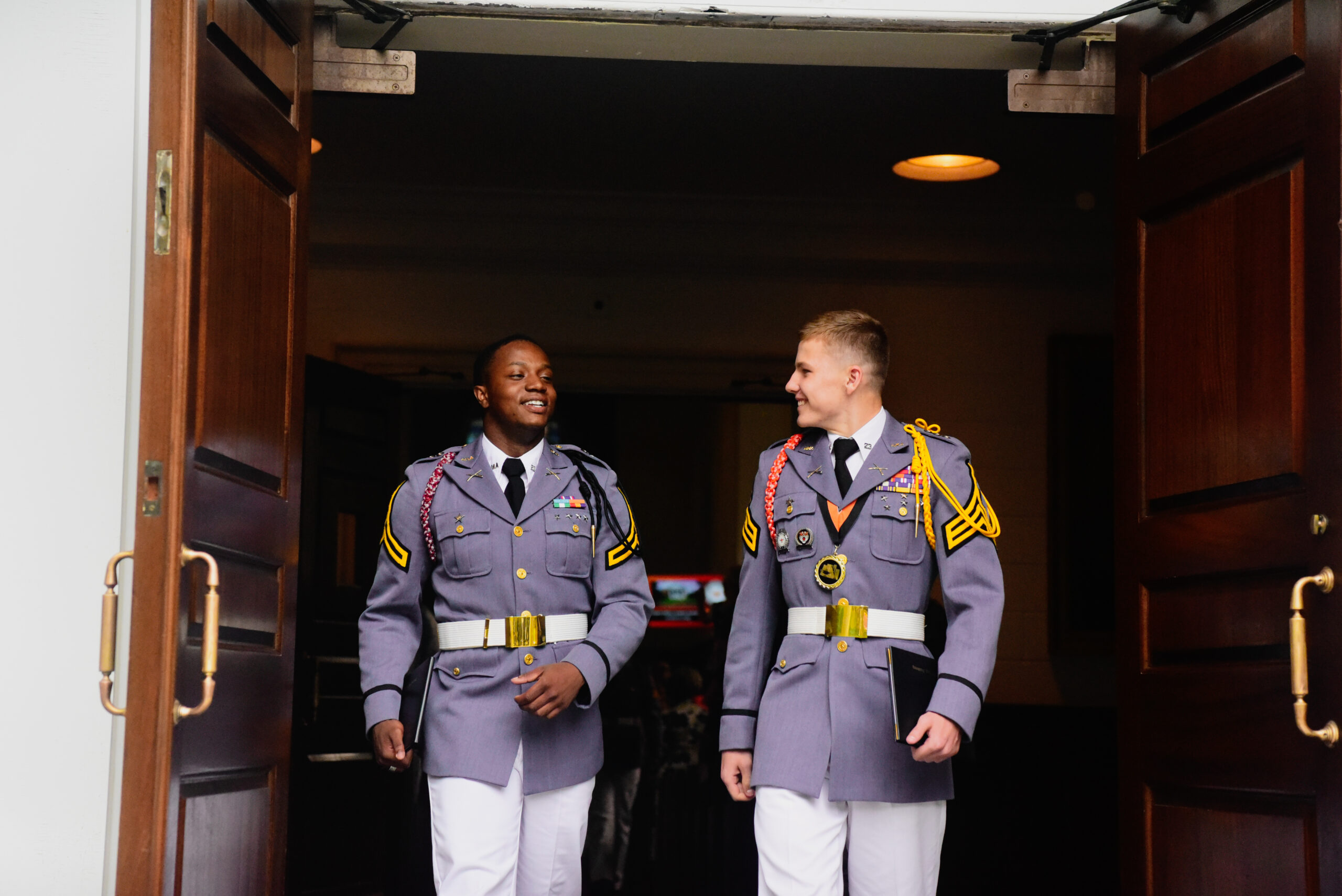Two cadets walking out of chapel talkin with each other.